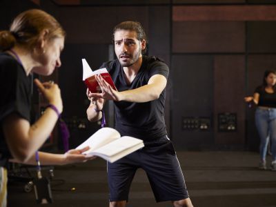 A man holds a text infront of him, his arm is out